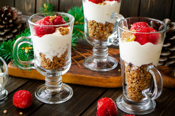 Holiday dessert with cream, muesli, fresh strawberry, sauce, cheesecake and yogurt on rustic wooden background close up