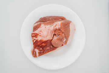 A piece of raw meat on a white plate