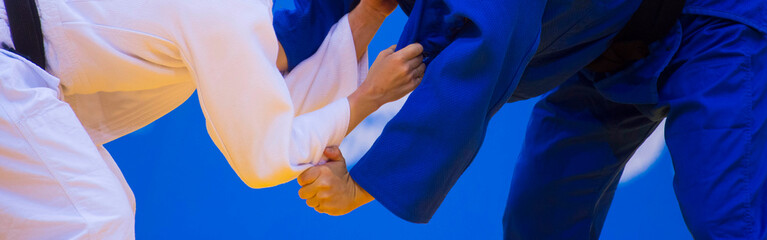 Two judo fighters in white and blue uniform. Martial arts competition - sambo, judo, karate, jiu...