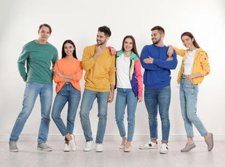 Group of young people in stylish jeans near white wall