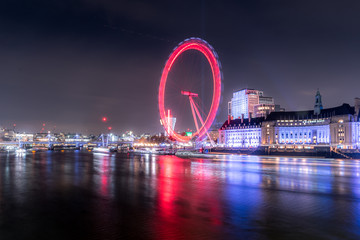 Long exposure of the London eye along the Thames at night with red circle - obrazy, fototapety, plakaty