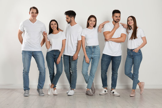 Group of young people in stylish jeans near white wall