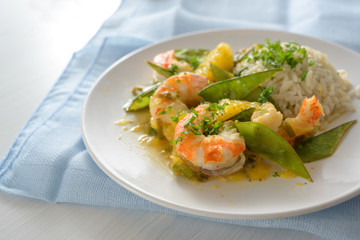 Seafood meal from fried tiger prawn shrimps with sugar peas, oranges and rice