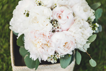 Pretty and tender light pastel colored bridal bouquet with white and pink peonies in wooden box