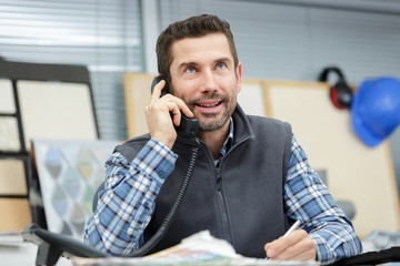 smiling man using mobile phone in office