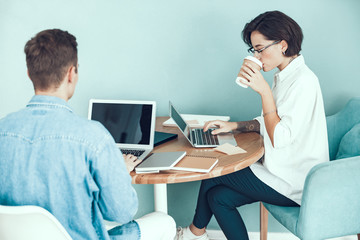 Young woman is drinking hot drink in office