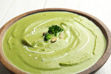 Bowl of delicious broccoli cream soup with pumpkin seeds, closeup