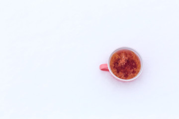 A pink mug with a drink is standing in the snow on a street in winter