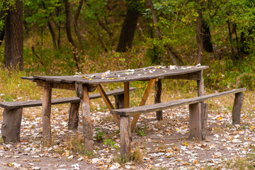 A table and two benches from a rough log house. Recreation area in the forest