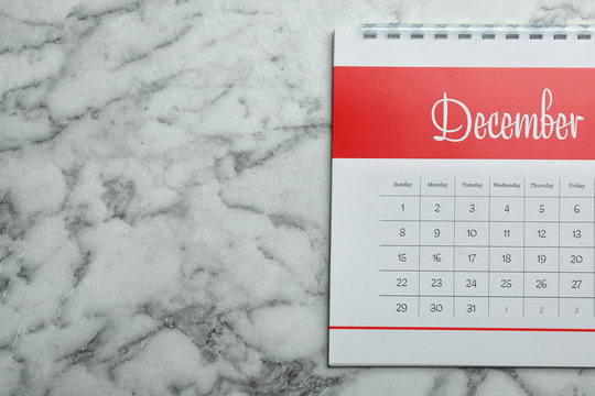 December calendar on marble background, top view. Space for text