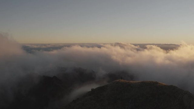 Hiking man silhouette in misty mountains aerial video. Drone Flight over Man mountaineer climbing rock mountain. Hiker silhouette on mountain aerial view 4K.