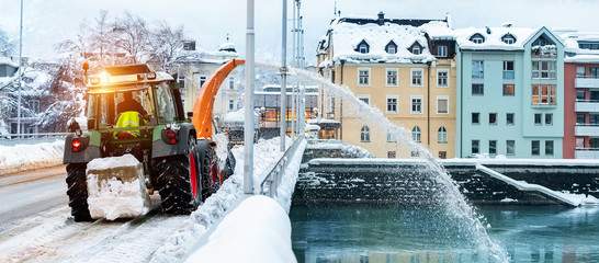 Heavy municipal services machinery removing snow from city streets. Big tractor snowblower blowing...