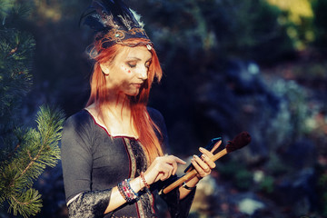 beautiful shamanic woman with headband and cell phone in the nature.