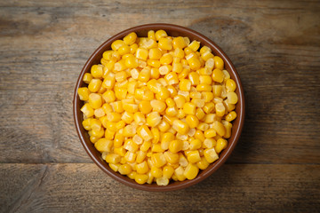 Delicious canned corn in bowl on wooden table, top view