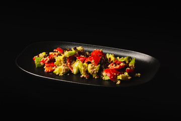 Raw paleo quinoa kale salad in a black plate on the dark background, with copy-paste space. Healthy, vegan, vegetarian and diet eating food.