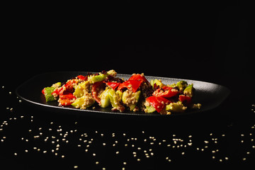 Raw paleo quinoa kale salad in a black plate on the dark background, with copy-paste space. Healthy, vegan, vegetarian and diet eating food.