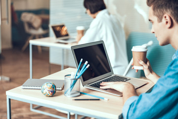 Young man is holding coffee at workplace