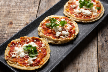 Mexican sopes with red sauce and fresh cheese on wooden background