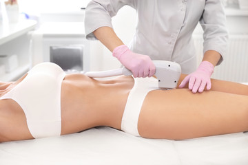 Young woman undergoing laser epilation procedure in beauty salon, closeup
