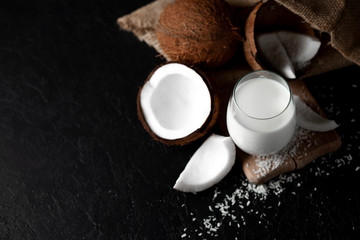 fresh coconut milk in a glass against a dark background, coconut cosmetic cream, milkshake with coconut slices