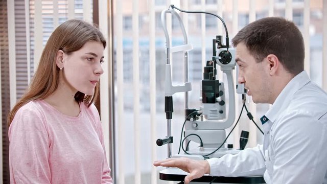 Ophthalmology treatment in the cabinet - young smiling woman having a consultation with an optometry doctor