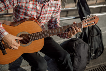 Male hands holding guitar and playing in the street