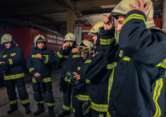 Fototapeta premium Firemen preparing for emergency service. Firefighters putting on gloves.