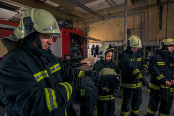 Firemen preparing for emergency service. Firefighters putting on gloves.