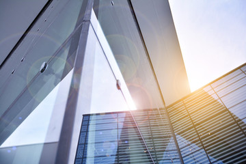 Sun rays light effects on urban buildings. Abstract image of looking up at modern glass and concrete building. Architectural exterior detail of office building.