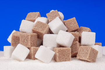 Heap of cane sugar and white sugar on a blue background