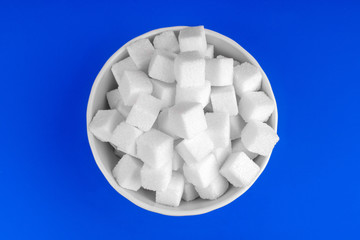 bowl of white sugar on a blue background top view