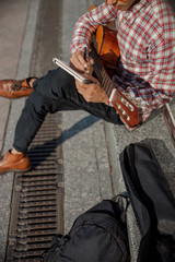 Cropped photo of guitarist holding notebook in the street