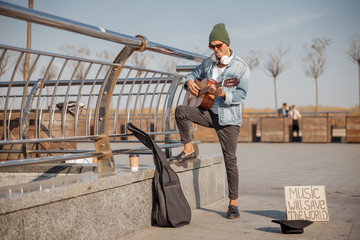 Stylish guy with guitar standing in the city