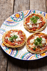 Mexican sopes with red sauce and fresh cheese on wooden background