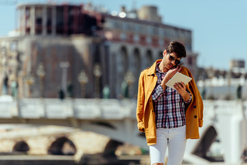 Fototapeta premium Stylish man relaxing while walking at boardwalk near river