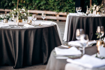 Festive banquet. Round tables which are beautifully decorated with plates, candles and a beautiful composition of flowers