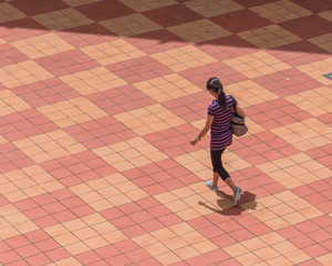 Asian person walking along patio tiles outdoor sing Singapore directly above view