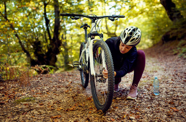 Woman repairing bicycle tire in forest