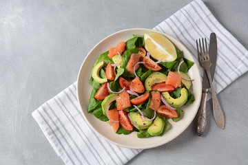 Mediterranean Avocado Salmon Salad with spinach, cherry tomatoes, avocado and red onion dressing. Concept for a tasty and healthy meal. Vegan food