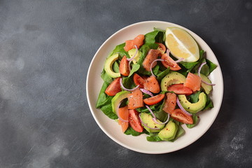 Mediterranean Avocado Salmon Salad with spinach, cherry tomatoes, avocado and red onion dressing. Concept for a tasty and healthy meal. Vegan food