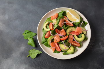 Mediterranean Avocado Salmon Salad with spinach, cherry tomatoes, avocado and red onion dressing. Concept for a tasty and healthy meal. Vegan food
