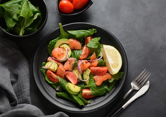 Mediterranean Avocado Salmon Salad with spinach, cherry tomatoes, avocado and red onion dressing. Concept for a tasty and healthy meal. Vegan food