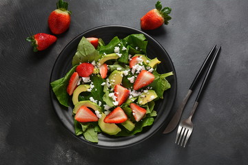 Summer Strawberry Salad with spinach, feta cheese, avocado, balsamic vinegar and olive oil in a plate. Vegan food. Healthy food concept
