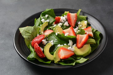 Summer Strawberry Salad with spinach, feta cheese, avocado, balsamic vinegar and olive oil in a plate. Vegan food. Healthy food concept