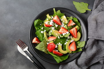 Summer Strawberry Salad with spinach, feta cheese, avocado, balsamic vinegar and olive oil in a plate. Vegan food. Healthy food concept