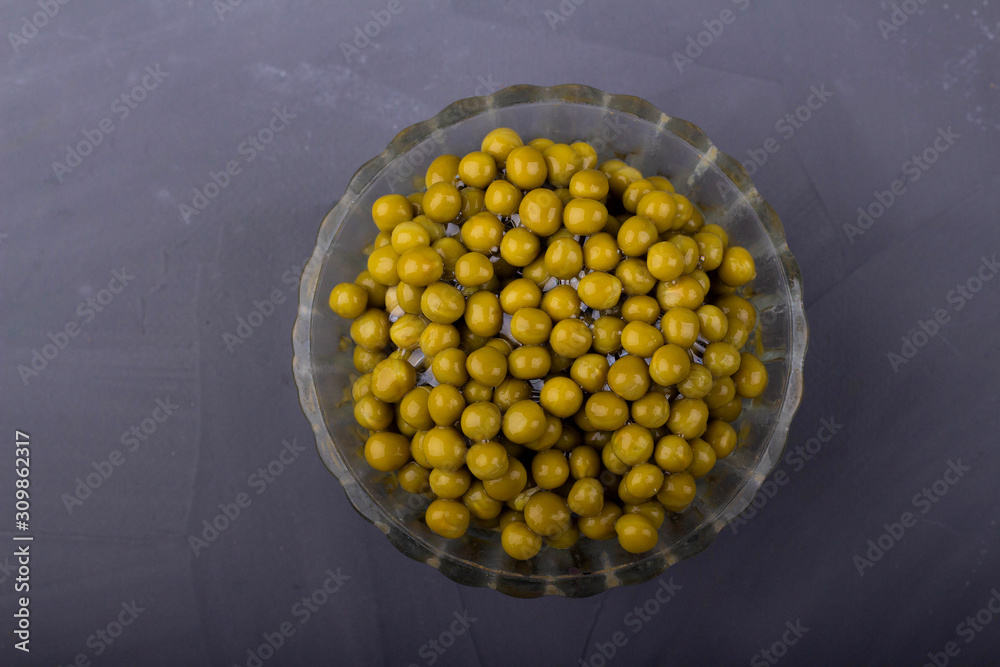 Wall mural canned green peas in a glass bowl on a gray background