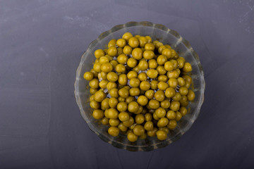 Canned green peas in a glass bowl on a gray background
