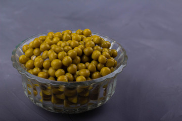 Canned green peas in a glass bowl on a gray background