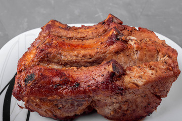 Roast pork on a white plate on a gray background