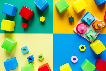 Obraz premium Wooden kids toys on colourful paper. Educational toys blocks, pyramid. Toys for kindergarten, preschool or daycare. Copy space for text. Top view 